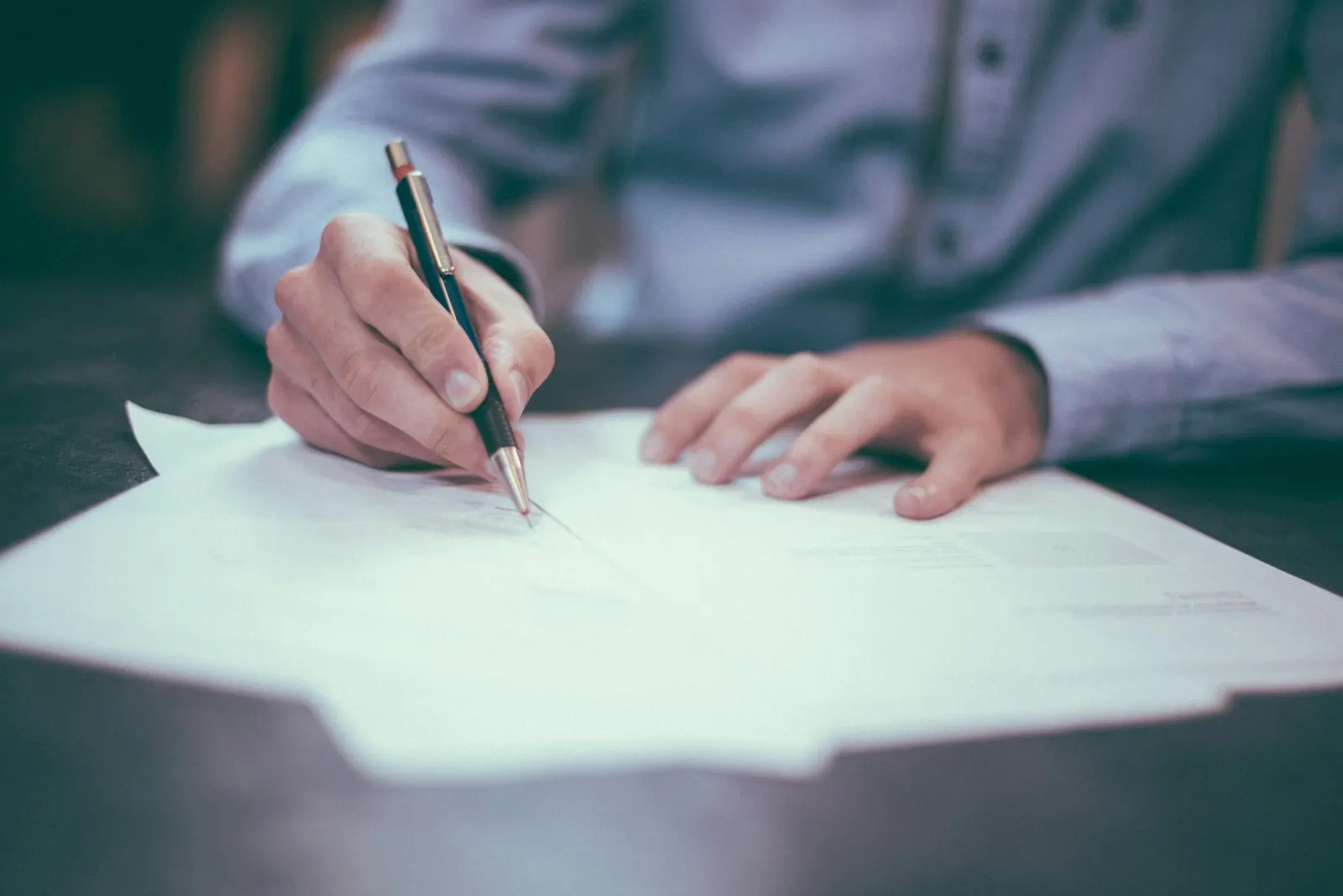Person signing paperwork at a desk