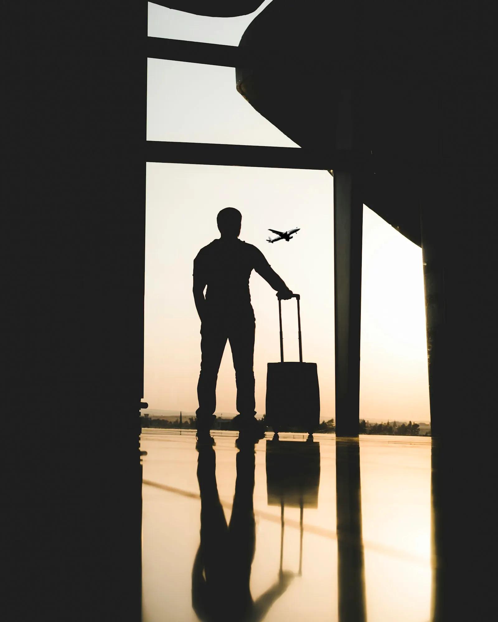 Traveller silhouetted beside an airport window
