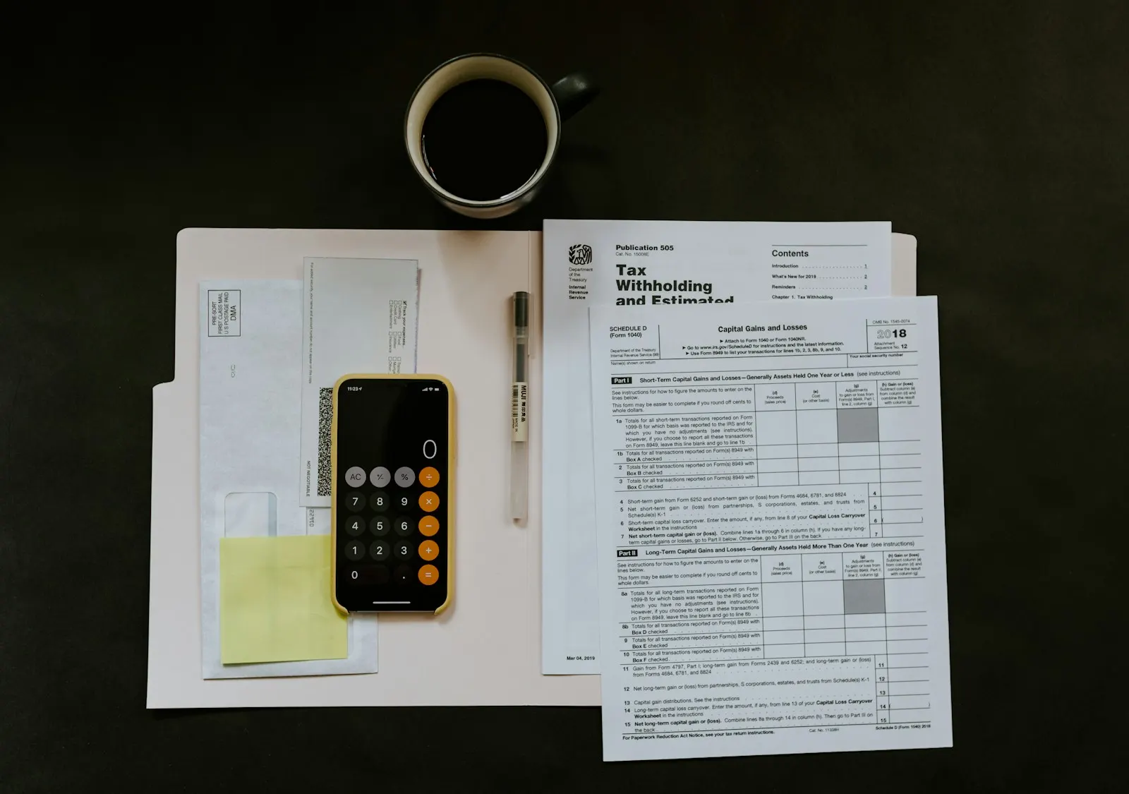 Financial forms beside a calculator and cup